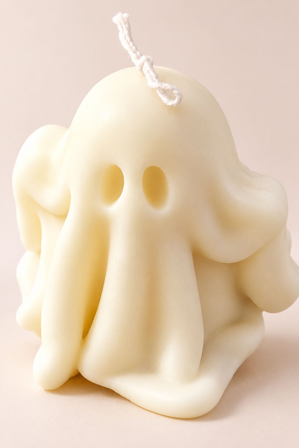 Close-up of the oval eyes and sculpted folds of the ivory Boo ghost soy candle.