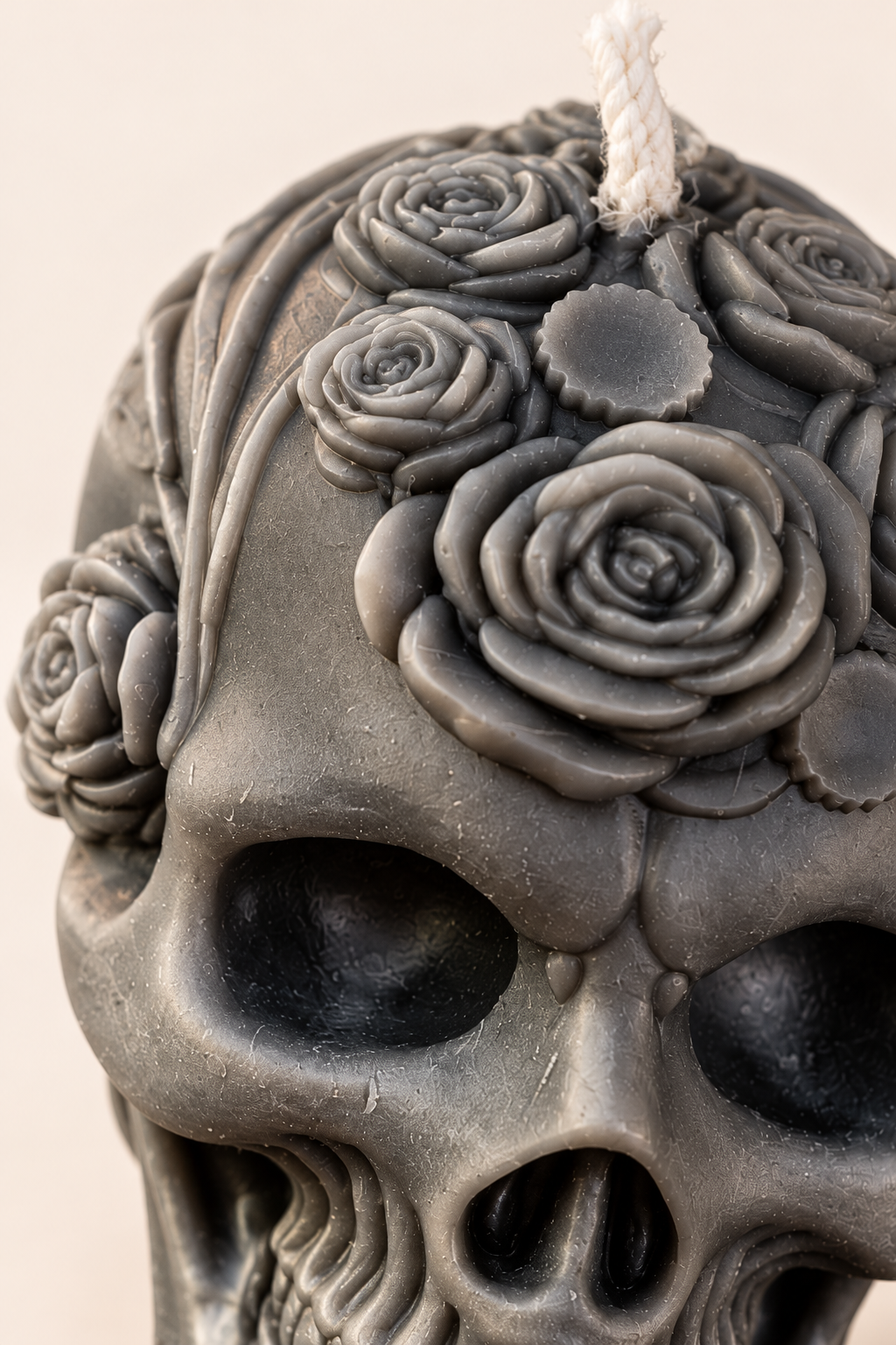 Close-up of the sculpted roses and eye sockets of the charcoal Gothic Rose Skull soy candle.